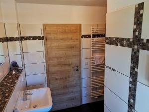 a bathroom with a sink and a wooden door at Ferienhaus Papstdorf Sächsische Schweiz 18 in Kurort Gohrisch +13 photos