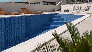 Villa Helena في تروغير: حمام سباحة وبلاط ازرق على جانب المنزل