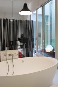 a white bath tub in a room with windows at Leopold5 Luxe-Design Apartment in Ostend