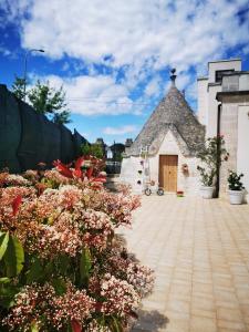 a building with a tower with a door and flowers at Trullo Suite in Cisternino