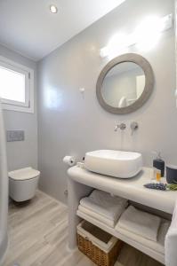 uma casa de banho branca com um lavatório e um espelho em Orkos Naxian Wave 2 em Mikri Vigla