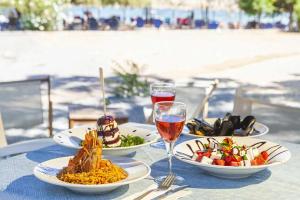a table with plates of food and a glass of wine at Vlichos Studio Apartment in Hydra
