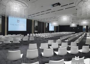 a conference room with white chairs and a screen at The Met Hotel Thessaloniki, a Member of Design Hotels in Thessaloniki