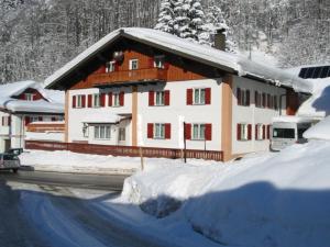 un grand bâtiment avec de la neige sur le côté d'une route dans l'établissement Haus Jochum, à Langen am Arlberg