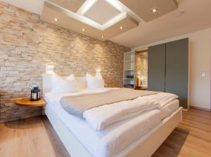 uma grande cama branca num quarto com uma parede de tijolos em Appartementhaus EifelAdventures em Berlingen