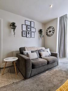 uma sala de estar com um sofá e um relógio na parede em Sandalwood Apartment - Saltburn by the Sea em Saltburn-by-the-Sea
