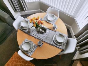 uma mesa de madeira com pratos e um vaso de flores em Sandalwood Apartment - Saltburn by the Sea em Saltburn-by-the-Sea