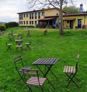 un grupo de mesas de picnic y sillas en un campo en Hotel Rural La Llosa de Fombona, en Luanco