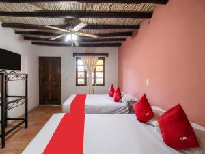 Hacienda Del Angel في باراس دي لا فونتي: غرفة نوم بسريرين ومخدات حمراء وسقف