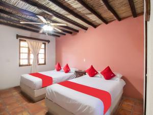 Hacienda Del Angel في باراس دي لا فونتي: سريرين في غرفة ذات أغطية حمراء وبيضاء