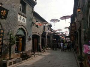 a group of people walking down a street with umbrellas at 7days Inn·Zibo Zhoucun Taoyuan Ginza Branch in Zibo