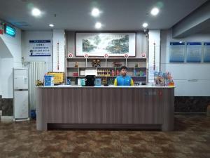 a man standing at the counter of a store at 7days Inn·Zibo Zhoucun Taoyuan Ginza Branch in Zibo