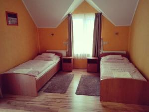 two beds in a room with a window at Főnix Apartmanház in Nagypáli