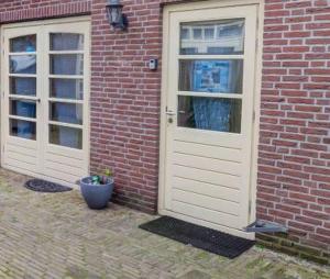 zwei weiße Türen auf einem Backsteingebäude mit einem Topf in der Unterkunft Appartement Villa Eva Rosa in Wijk aan Zee