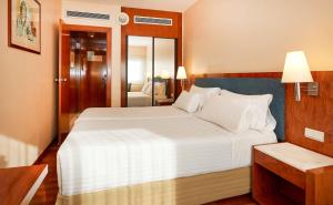 1 dormitorio con 1 cama blanca grande y espejo en NH Barcelona Entenza en Barcelona