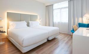 a bedroom with a large bed and a large window at NH Bilbao Deusto in Bilbao
