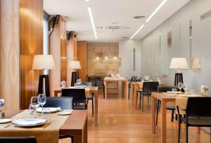 a dining room with tables and chairs and lamps at NH Zamora Palacio del Duero in Zamora
