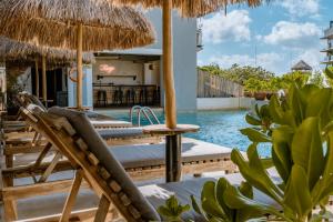 a pool with chairs and umbrellas next to a resort at Caribbean Paradise Hotel Boutique & Spa by Paradise Hotels - 5th Av Playa del Carmen in Playa del Carmen