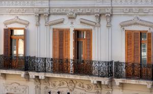 Edificio blanco con persianas marrones y balcón en NH Collection Colón Valencia, en Valencia
