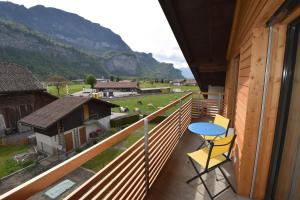 a balcony with a blue table and chairs and mountains at Ferienwohnung Gemeindematte in Meiringen