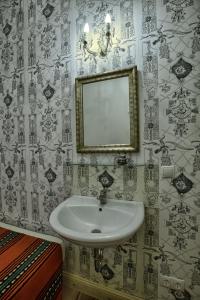 ein Bad mit einem Waschbecken und einem Wandspiegel in der Unterkunft Pension Friedrich-Wilhelm in Berlin