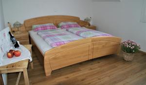 ein Holzbett in einem Schlafzimmer mit einem Tisch und einem Siddx-Bett in der Unterkunft Gasthof & Gästehaus Trummer in Horitschon