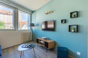 Habitación con pared azul, TV y mesa. en Le 15-GregIMMO-Appart'Hôtel en Montbéliard