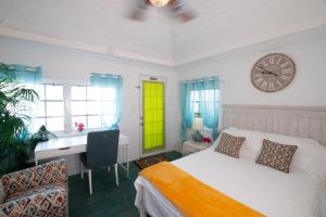 1 dormitorio con cama, escritorio y reloj en Garden Cottage - At Orange Hill en Nassau