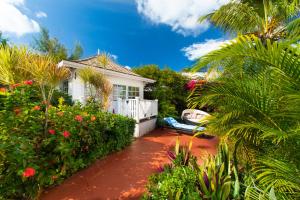 a house with a garden with flowers and plants at Garden Cottage - At Orange Hill in Nassau