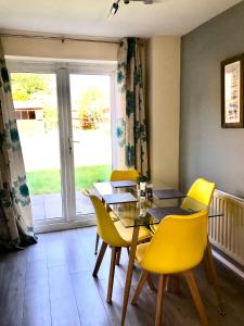 a dining room with a table and yellow chairs at Kettering Leisure Holiday Home in Kettering
