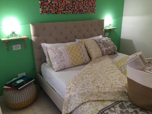 sypialnia z łóżkiem z poduszkami i zieloną ścianą w obiekcie Intra Rooms w mieście Olbia