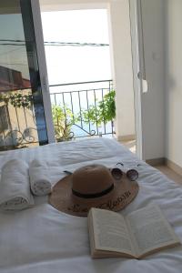 um chapéu e óculos e um livro numa cama em Apartmani Kasija em Dobra Voda