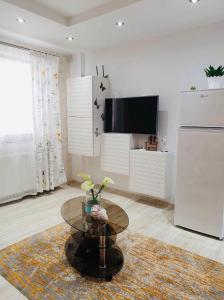 een woonkamer met een tafel en een televisie bij Apartament Manu in Mamaia Nord – Năvodari