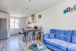 ein Wohnzimmer mit einem blauen Sofa und einer Küche in der Unterkunft Le 101-GregIMMO-Appart'Hôtel in Audincourt