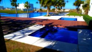 uma piscina com água azul e palmeiras em CASA EM CONDOMÍNIO - 3 dormitórios - LAZER COMPLETO - Xangri-lá em Xangri-lá