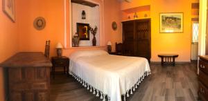 um quarto com uma cama branca e paredes cor-de-laranja em Casa Tecolote em Guanajuato