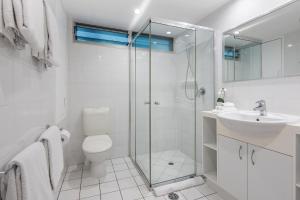 a bathroom with a shower and a toilet and a sink at Poinciana Lodge - 2 bedroom - on Hamilton Island by HIHA in Hamilton Island