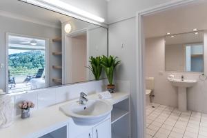 a bathroom with a sink, mirror, and tub at 2 Bedroom Poinciana Lodge in Hamilton Island