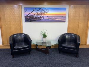 a living room with two chairs and a painting on the wall at Northpoint Apartments in Port Macquarie