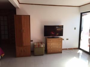 uma sala de estar com televisão e cómoda em HOSTAL CAUQUENES em De Cauquenes