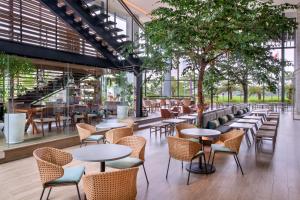 un ristorante con tavoli, sedie e un albero di Mercure Tangerang BSD City a Tangerang