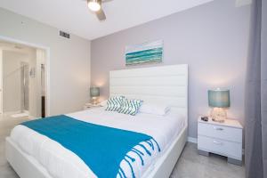 a white bedroom with a large bed with a blue blanket at (HM207) Storey Lake Condo 2/2, Free Waterpark in Kissimmee