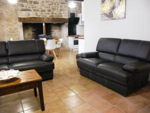 a living room with black leather furniture and a fireplace at LOU CHASTEL, DEMEURE PERIGOURDINE CLIMATISEE avec PISCINE PRIVEE et CHAUFFEE in La Bachellerie
