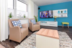 sala de estar con 2 sillas y TV de pantalla plana en Haus zur Möwe, en Bensersiel