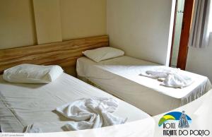 two beds in a small room with white sheets at Hotel Mirante do Porto in Aparecida
