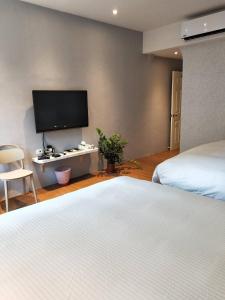 a bedroom with two beds and a flat screen tv at Light Blue Hostel in Hengchun