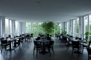 a dining room with tables and chairs and windows at Hotel zwischen den Seen in Waren