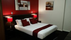 a bedroom with a large bed with red walls at ibis Styles Broken Hill in Broken Hill