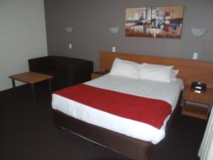 a bedroom with a large bed with a red blanket at ibis Styles Broken Hill in Broken Hill