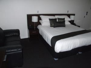 a bedroom with a large bed and a black chair at ibis Styles Broken Hill in Broken Hill
